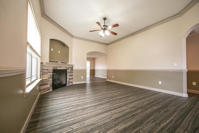 unfurnished living room featuring ornamental molding, ceiling fan, a stone fireplace, and dark hardwood / wood-style floors