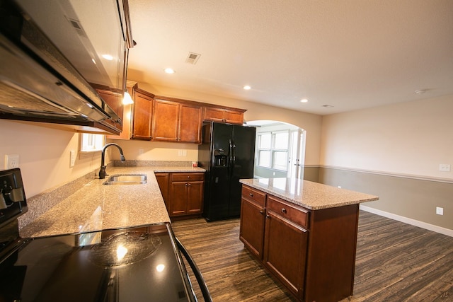 kitchen with black fridge, sink, range, a kitchen island, and dark wood-type flooring