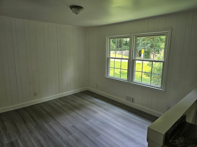 spare room featuring hardwood / wood-style floors and wood walls