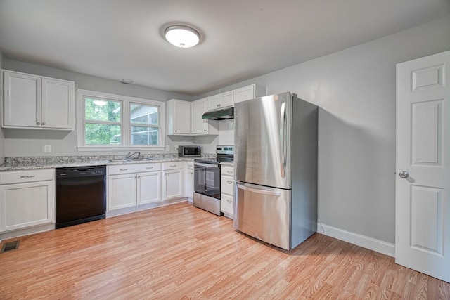 kitchen featuring light stone counters, sink, white cabinetry, light wood-type flooring, and appliances with stainless steel finishes