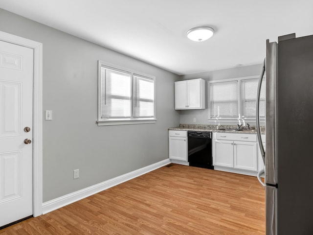 kitchen featuring black dishwasher, stainless steel refrigerator, a healthy amount of sunlight, and light hardwood / wood-style flooring