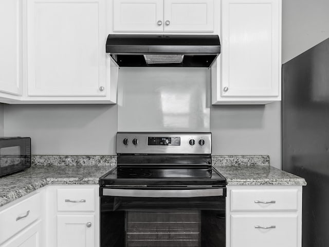 kitchen featuring white cabinetry, stainless steel electric range oven, black fridge, and light stone counters