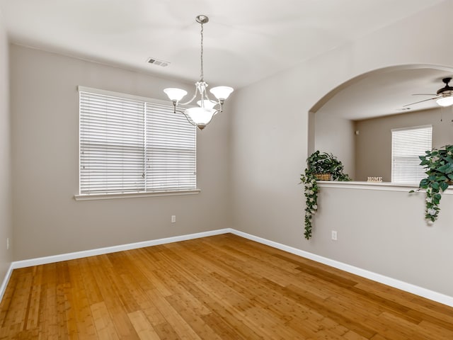 spare room featuring hardwood / wood-style floors and ceiling fan with notable chandelier