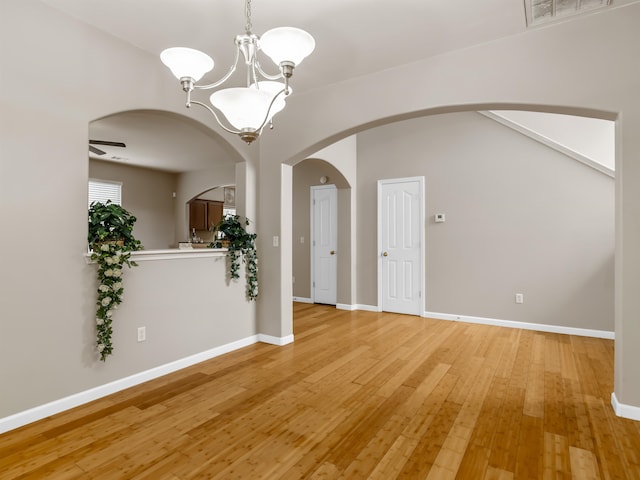 unfurnished room with ceiling fan with notable chandelier and light hardwood / wood-style flooring