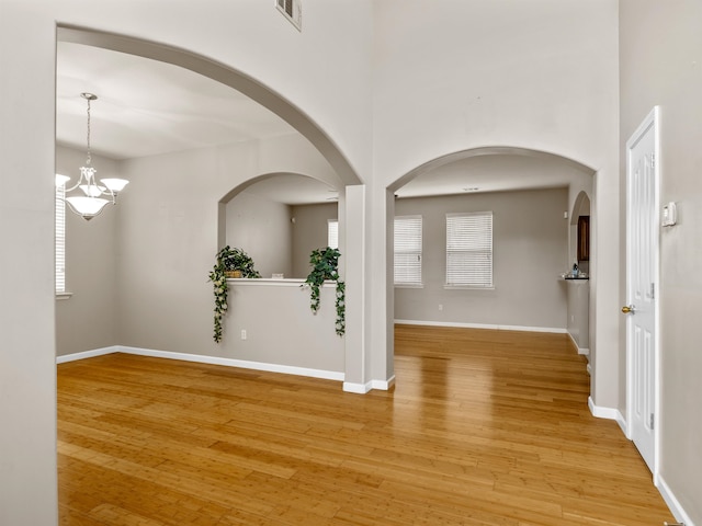 unfurnished room with a chandelier and light hardwood / wood-style flooring