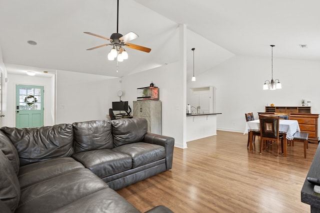 living room with sink, vaulted ceiling, light hardwood / wood-style floors, and ceiling fan with notable chandelier