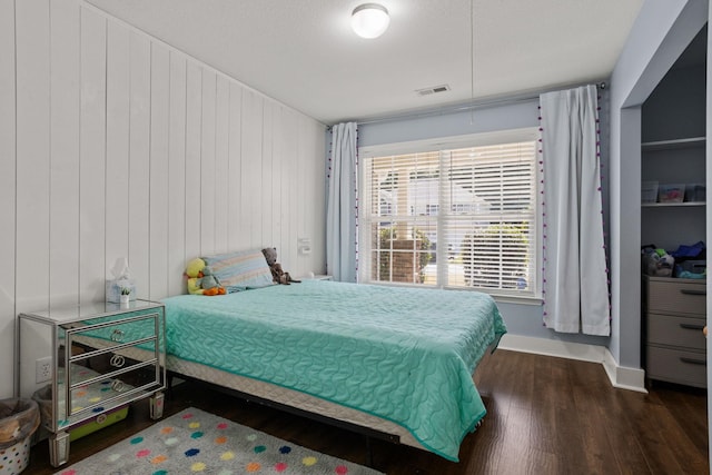 bedroom with dark wood-type flooring and wood walls