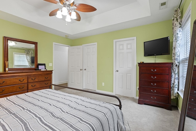 carpeted bedroom with a tray ceiling and ceiling fan