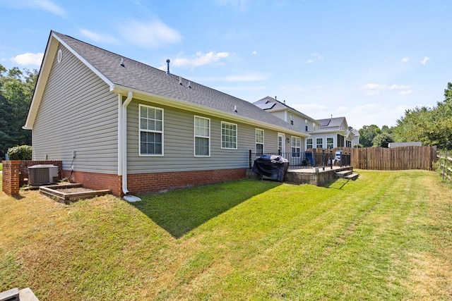 back of house with central air condition unit and a yard