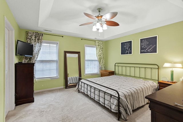 carpeted bedroom featuring ceiling fan and a tray ceiling