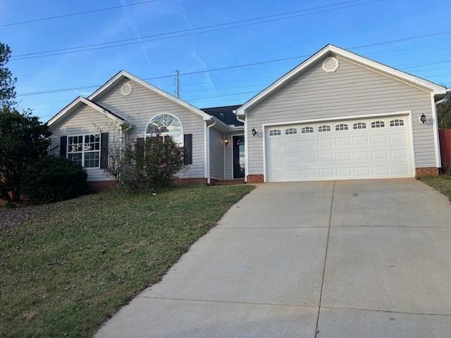 ranch-style home with a garage and a front lawn