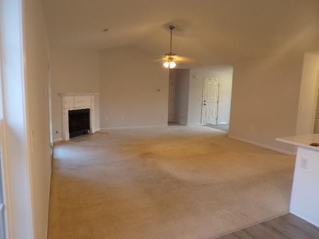 unfurnished living room featuring lofted ceiling, ceiling fan, and light carpet