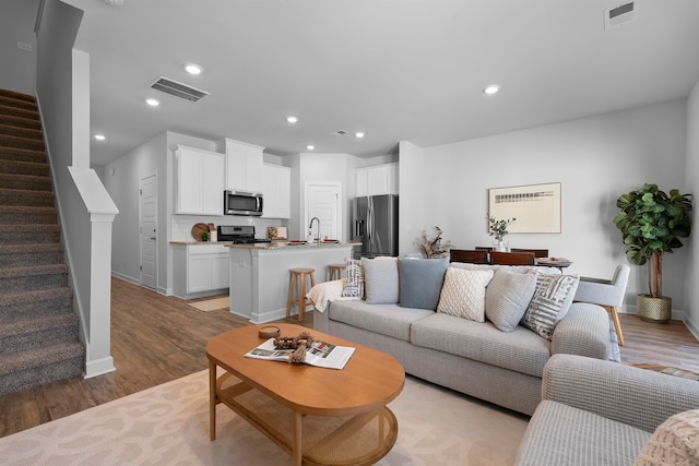 living room featuring sink and light hardwood / wood-style flooring