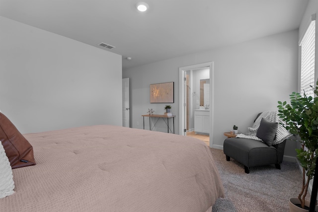 bedroom featuring ensuite bathroom and light colored carpet