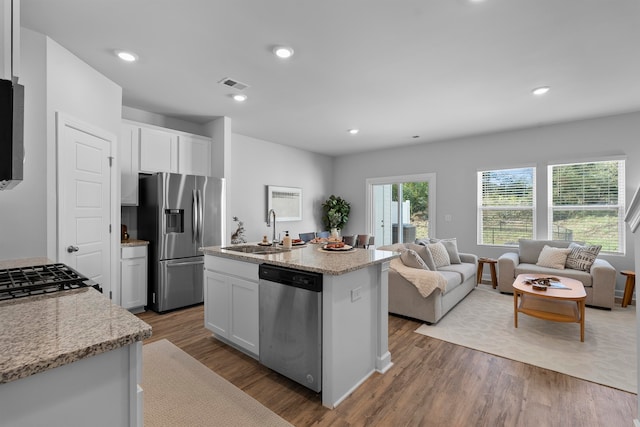 kitchen with a center island with sink, hardwood / wood-style flooring, sink, white cabinetry, and appliances with stainless steel finishes