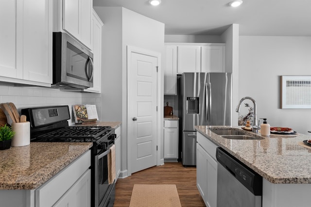 kitchen featuring light stone counters, appliances with stainless steel finishes, hardwood / wood-style floors, sink, and white cabinets