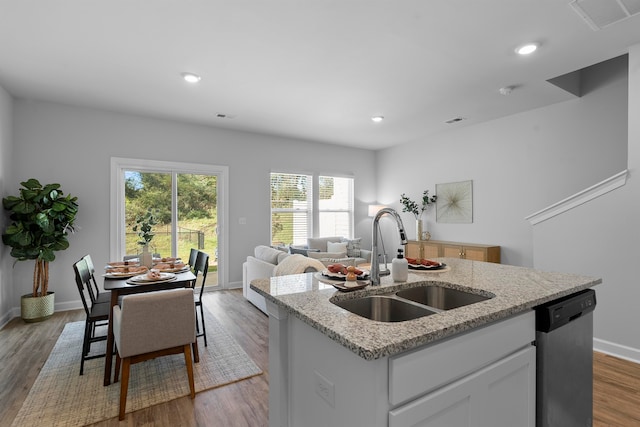 kitchen with hardwood / wood-style flooring, sink, a kitchen island with sink, stainless steel dishwasher, and white cabinetry