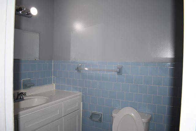 bathroom with vanity, toilet, and tile walls