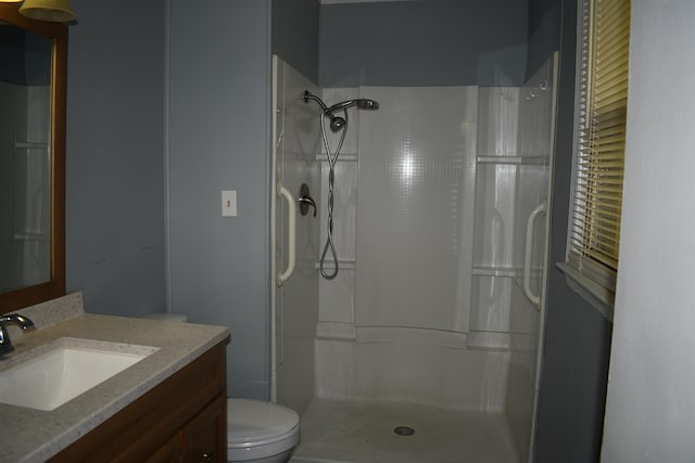 bathroom with toilet, vanity, and tiled shower