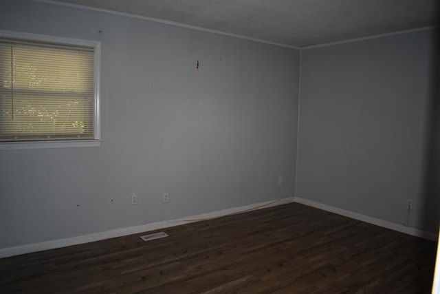 empty room featuring crown molding, a textured ceiling, and dark hardwood / wood-style flooring