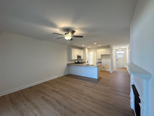 kitchen featuring baseboards, dark wood finished floors, white cabinets, appliances with stainless steel finishes, and a peninsula