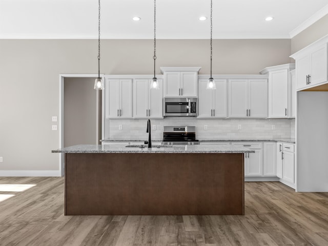 kitchen with hanging light fixtures, sink, a kitchen island with sink, and appliances with stainless steel finishes