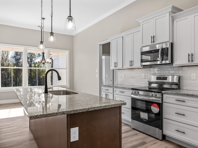 kitchen with light hardwood / wood-style floors, stainless steel appliances, sink, white cabinetry, and decorative light fixtures