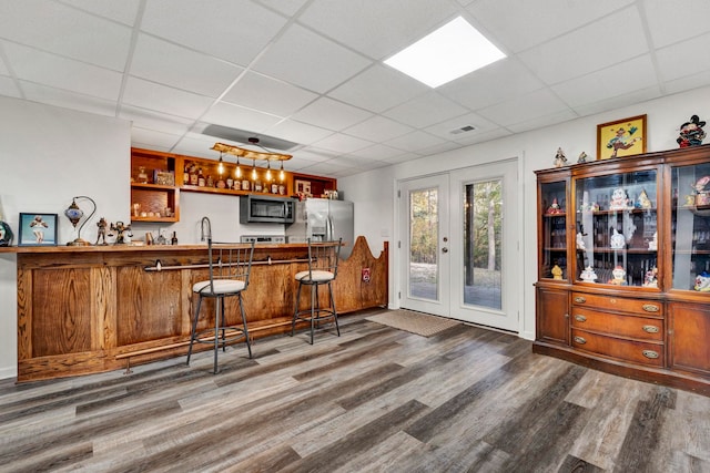 bar with hardwood / wood-style floors, appliances with stainless steel finishes, a drop ceiling, and french doors