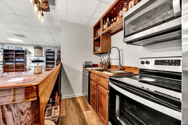 kitchen featuring sink, a drop ceiling, appliances with stainless steel finishes, and light hardwood / wood-style flooring