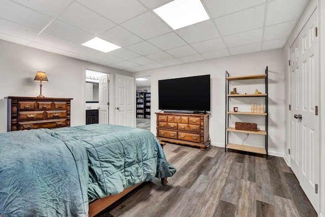 bedroom featuring ensuite bath, a paneled ceiling, and hardwood / wood-style floors