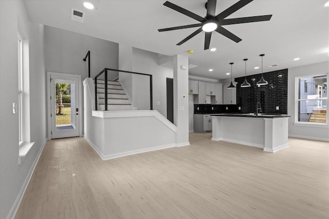 unfurnished living room featuring ceiling fan, sink, and light hardwood / wood-style flooring