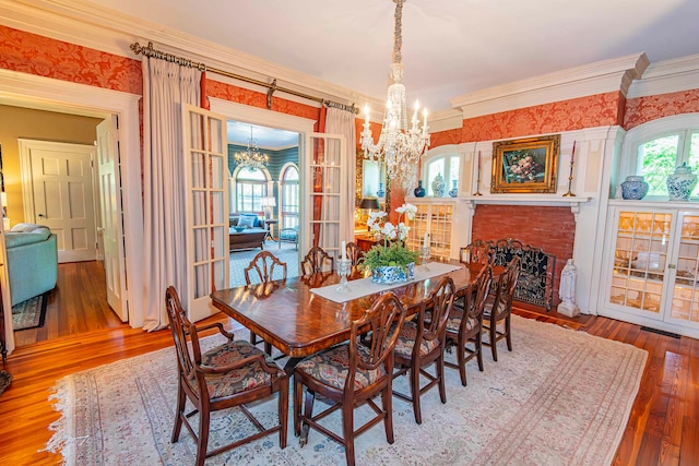 dining room featuring ornamental molding, a fireplace, wood-type flooring, and a notable chandelier