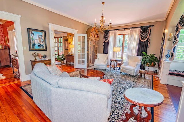 living room with ornamental molding, hardwood / wood-style floors, a healthy amount of sunlight, and a chandelier