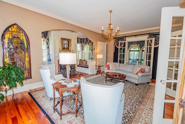 living room with an inviting chandelier, hardwood / wood-style floors, french doors, and crown molding