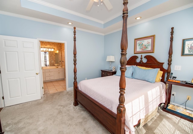 carpeted bedroom with ensuite bath, ceiling fan, crown molding, and a tray ceiling