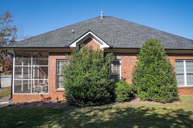 back of property with a sunroom and a lawn