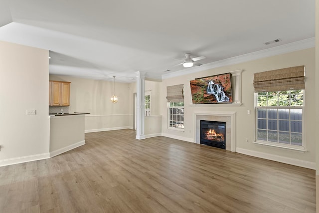 unfurnished living room with hardwood / wood-style flooring, crown molding, decorative columns, and ceiling fan