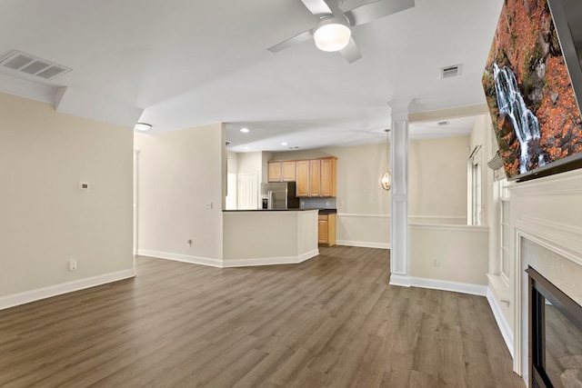 unfurnished living room with hardwood / wood-style flooring, ceiling fan, and ornate columns