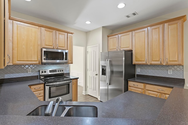 kitchen featuring backsplash, appliances with stainless steel finishes, sink, and light hardwood / wood-style floors