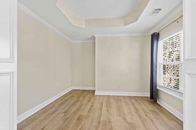 spare room featuring light wood-type flooring, crown molding, and a tray ceiling