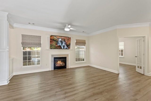 unfurnished living room with hardwood / wood-style floors, ceiling fan, a tile fireplace, and ornamental molding