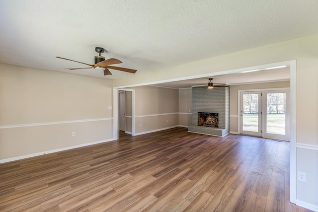 unfurnished living room with a textured ceiling, wood-type flooring, ceiling fan, and a fireplace