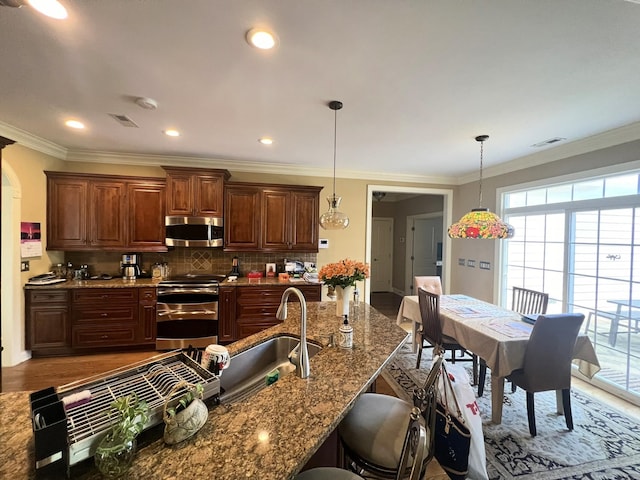 kitchen with hardwood / wood-style flooring, a breakfast bar area, sink, pendant lighting, and appliances with stainless steel finishes