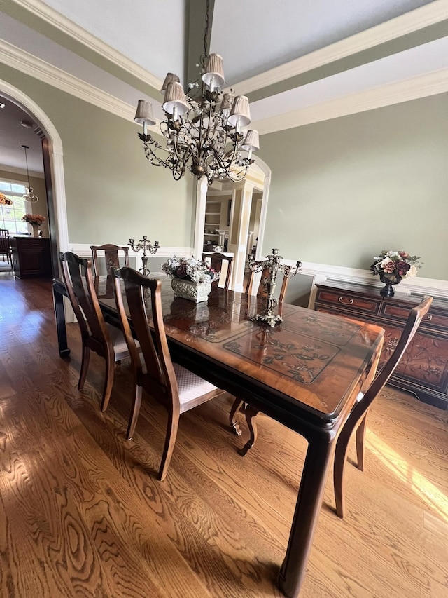 dining space with hardwood / wood-style floors, a chandelier, and ornamental molding