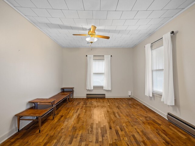 unfurnished room featuring hardwood / wood-style floors, a wealth of natural light, and baseboard heating