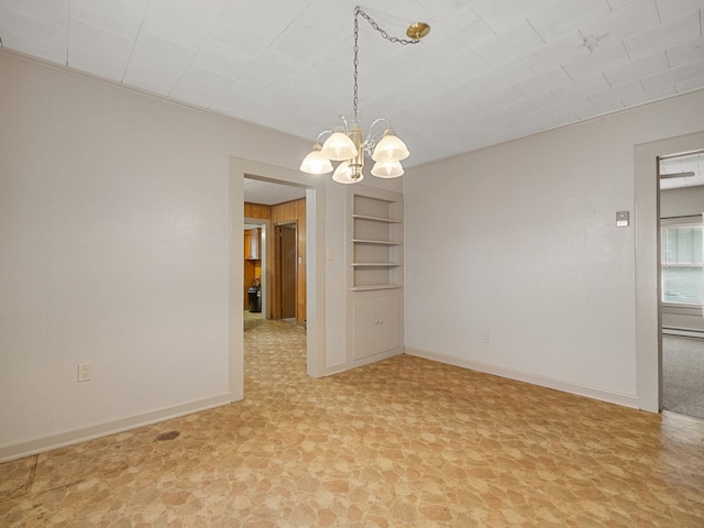 spare room with built in shelves, baseboard heating, and an inviting chandelier