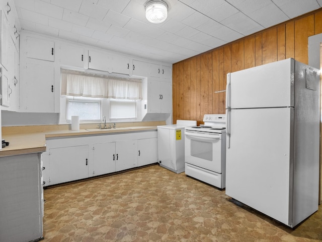 kitchen featuring wooden walls, white cabinetry, white appliances, and sink