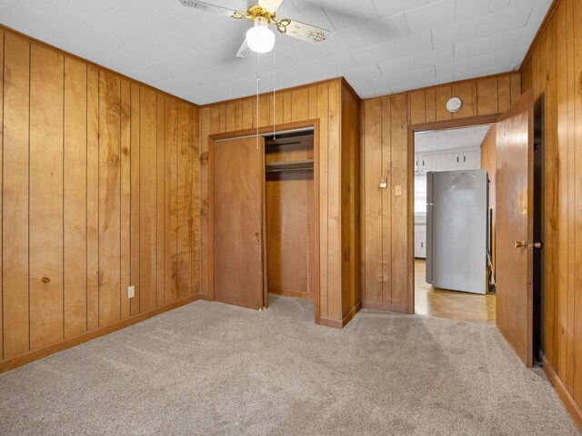 unfurnished bedroom featuring wooden walls and ceiling fan