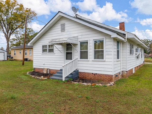 rear view of property featuring central AC unit and a lawn