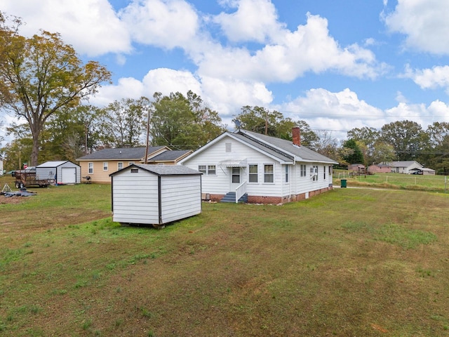 back of house with a yard and a storage shed